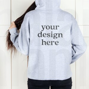 May include: A gray hooded sweatshirt with the text "your design here" printed on the back.