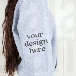 May include: A gray hooded sweatshirt with the text "your design here" printed on the left sleeve.