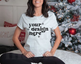 May include: A light gray t-shirt with rolled-up sleeves featuring the text "your design here" in a bold, black font, accented with snowflakes. The shirt is part of a clothing line.