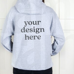 May include: A gray hooded sweatshirt with the text "your design here" printed on the back.