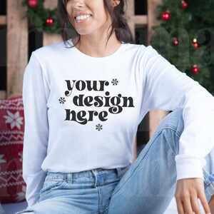 May include: White long-sleeve shirt with the text "your design here" in black lettering and snowflake accents.