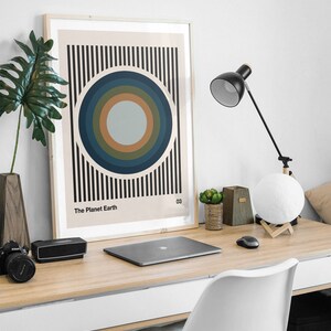 May include: A framed print with a minimalist design featuring concentric circles in shades of blue, green, and brown against a striped background. The print is titled "The Planet Earth" and numbered "03".