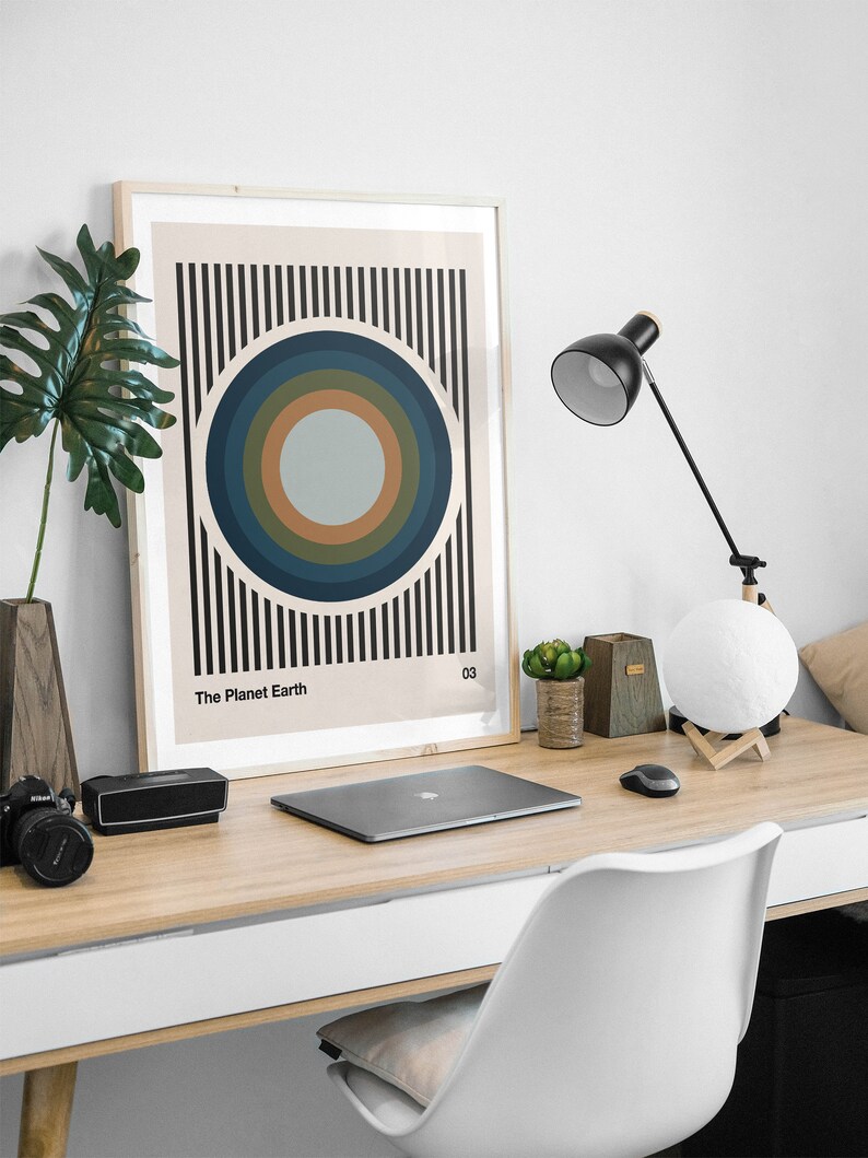 May include: A framed print with a minimalist design featuring concentric circles in shades of blue, green, and brown against a striped background. The print is titled "The Planet Earth" and numbered "03".