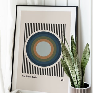 May include: A framed print with a black and white striped background and a concentric circle design in shades of blue, green, and brown. The text "The Planet Earth 03" is at the bottom of the print.