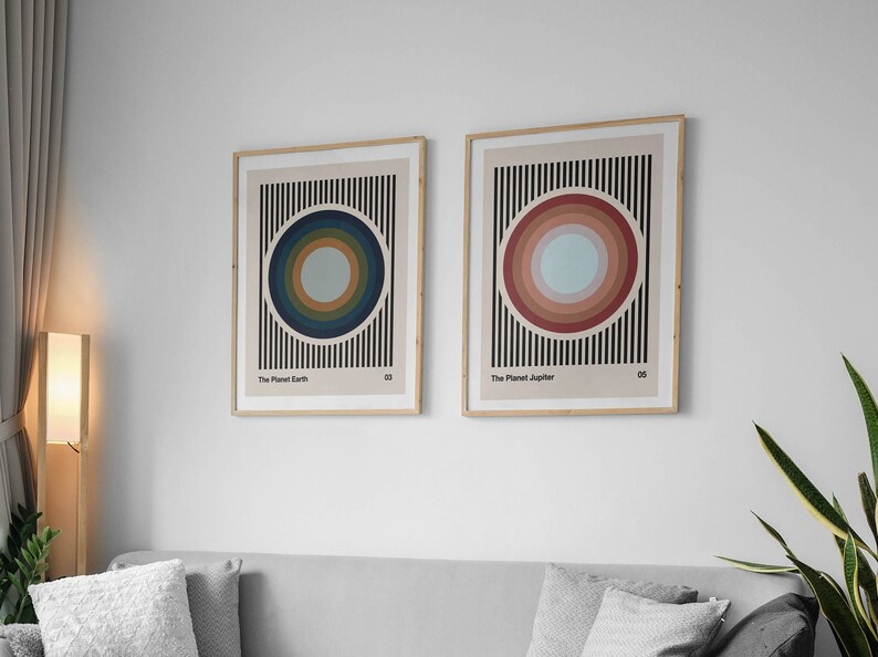 May include: Two framed prints with abstract geometric designs. The print on the left features a blue and green circle with black stripes. The print on the right features a red and pink circle with black stripes. The text on the prints reads "The Planet Earth" and "The Planet Jupiter".