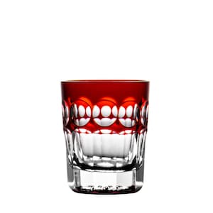 Könnte beinhalten: Ein klares, kurzes Trinkglas mit einem leuchtend roten Rand und dekorativen Schliffdetails. Das Glas hat ein geometrisches Muster am oberen Rand und einen klaren, schlichten Boden. Für Getränke.