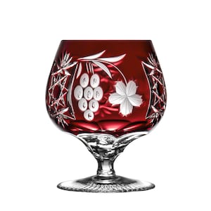 Könnte beinhalten: Ein rotes Kristallglas mit einem Trauben- und Blattdesign. Das Glas hat eine breite Schale und einen hohen Stiel.