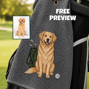 K&ouml;nnte beinhalten: Graues Golfhandtuch mit einem gestickten Golden Retriever, einer Golftasche und einem Golfball. Das Handtuch hat eine Waffelstruktur und einen goldfarbenen Haken. Der Text auf dem Handtuch lautet "FREE PREVIEW".