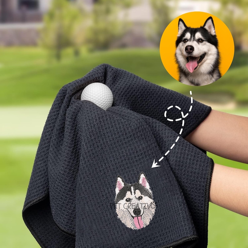 K&ouml;nnte beinhalten: Ein dunkelmarineblaues Golftuch mit einem gestickten Husky-Hund-Design und dem Text "PET CREATIVO". Ein wei&szlig;er Golfball ist in das Handtuch eingebettet. Das Bild enth&auml;lt auch ein kreisf&ouml;rmiges Bild eines Husky-Hundes.