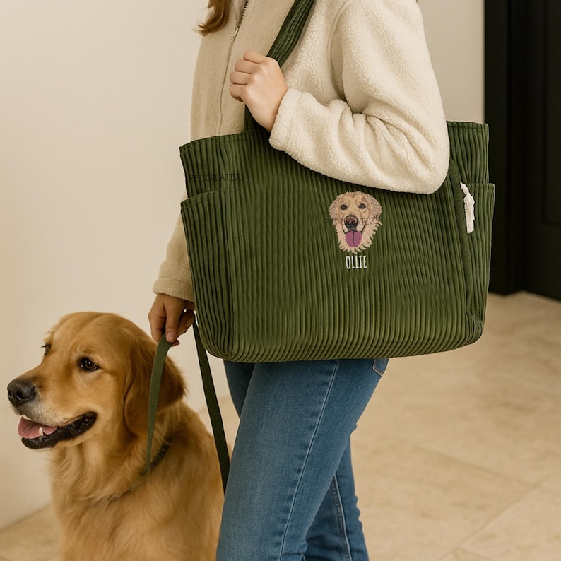 May include: Olive green corduroy tote bag with an embroidered golden retriever face and the name "Ollie" below. The bag has multiple pockets and is being held by a person. A golden retriever dog is on a leash next to the person.