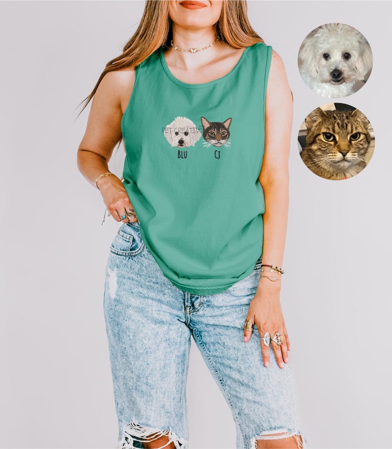 May include: Teal tank top with embroidered pet portraits of a dog and a cat, labeled "BLU" and "CJ". The words "PET CREATIVE" are above the portraits. The model is wearing light blue ripped jeans. Two pet portraits are in the background.
