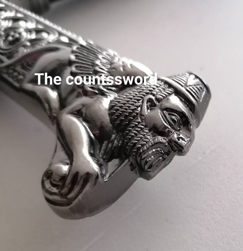May include: Close-up of a silver sword handle with a lion's head design. The text "The countssword" is visible on the handle. The handle has intricate details and a polished finish.