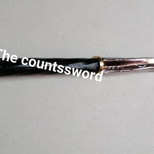 May include: A decorative dagger with a black handle and a silver blade. The handle is accented with gold-colored metal. The text "The countssword" is printed on the image.