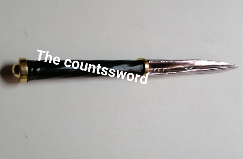 May include: A decorative dagger with a black handle and a silver blade. The handle is accented with gold-colored metal. The text "The countssword" is printed on the image.