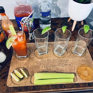 Könnte beinhalten: Holztablett mit Anweisungen zum Zubereiten eines klassischen Caesars. Das Tablett enthält vier Gläser, einen kleinen Metall-Jigger, eine Flasche Clamato-Saft, eine Flasche Wodka, eine Flasche scharfe Sauce, eine Flasche Lea & Perrins Worcestershire-Sauce, Salz, Pfeffer, Selleriestangen und Limettenspalten.