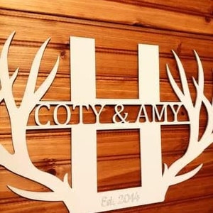 May include: White wooden cutout of the letter H with antlers on either side. The letter H is decorated with the text "COTY & AMY" and "Est. 2014".
