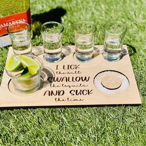 May include: Wooden serving tray with four shot glasses, a lime wedge, and a small dish of salt. The tray has the text "I lick the salt, swallow the tequila and suck the lime" engraved on it.