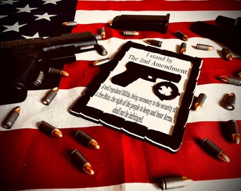 May include: A wooden sign with a black silhouette of a handgun and the text "I stand by The 2nd Amendment. A well regulated Militia, being necessary to the security of a free State, the right of the people to keep and bear Arms, shall not be infringed."