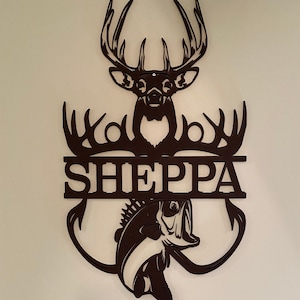 May include: Black metal wall art featuring a deer head with antlers, a fish, and the name "SHEPPA" in a split-letter design.