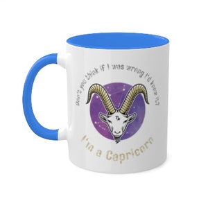 May include: White ceramic coffee mug with a blue rim. The mug features a purple and gold illustration of a Capricorn zodiac sign with the text "Don't you think if I was wrong I'd know it? I'm a Capricorn."