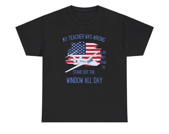 May include: Black t-shirt with a graphic of a plane flying over an American flag. The text reads "My teacher was wrong I do get paid to stare out the window all day."