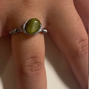 May include: A silver wire wrapped ring with a green gemstone.