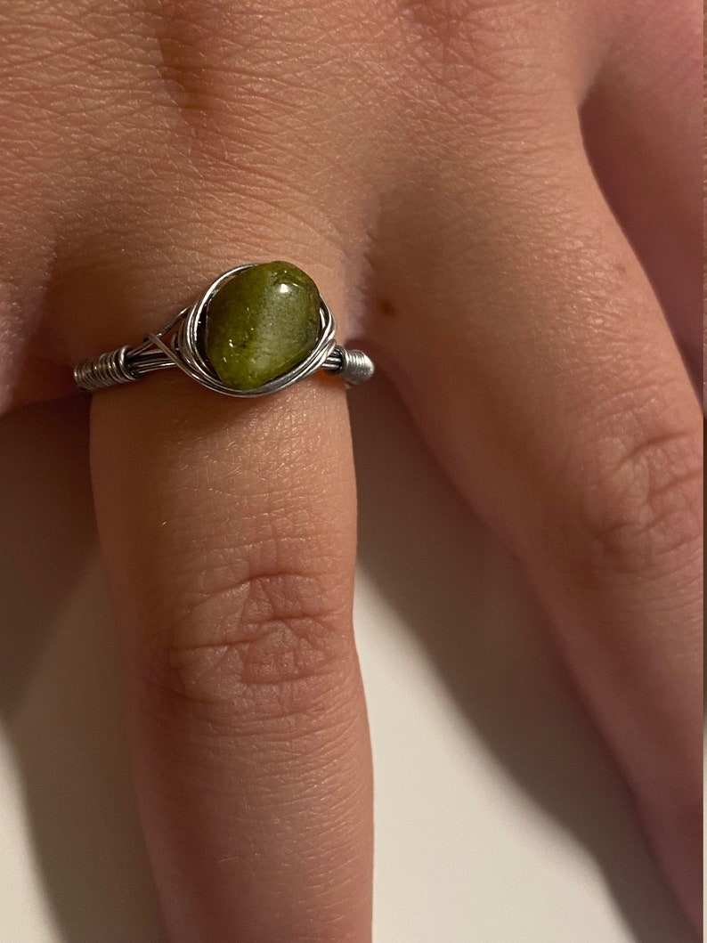 May include: A silver wire wrapped ring with a green gemstone.