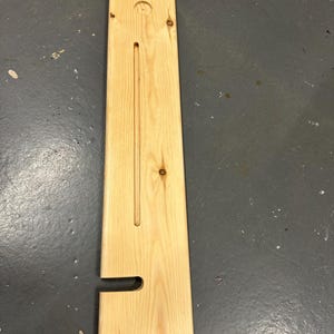 May include: A wooden shelf with a cutout for a soap dispenser and a groove for a bar of soap. The shelf is made of light wood and has a natural finish.