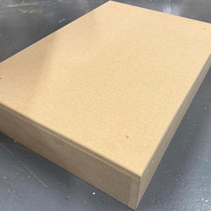 May include: A rectangular, unfinished wooden box in a light brown shade. The box is made from thick, robust material and seems to be assembled with small nails. The box is likely for storage or display.