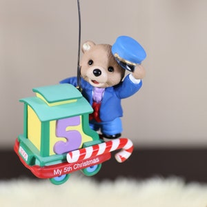 Hallmark Baby&#39;s Fifth Christmas. Child&#39;s Age Collection Featuring and Adorable Baby Bear on a Brightly Colored Peppermint Train Car.
