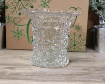 May include: A clear glass vase with a diamond pattern. The vase has a wide mouth and a round base.