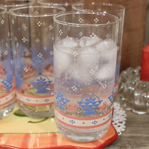May include: Tall, clear drinking glasses filled with ice and water. The glasses feature a blue and red floral design and small white dot pattern. The glasses are on a decorative tray.
