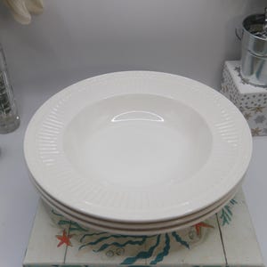 May include: A white ceramic mug with a black handle and the text "But First, Coffee" in a handwritten style. The mug is on a white surface. The mug is 4 inches tall.
