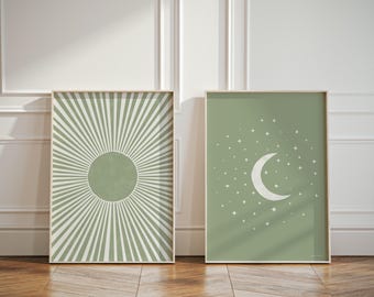 May include: Two framed prints with a green background. The print on the left features a white sunburst design with a green circle in the center. The print on the right features a white crescent moon and stars on a green background.