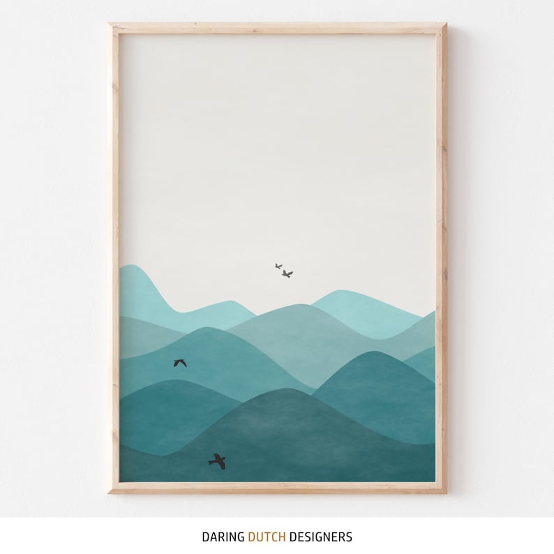 May include: Abstract art print featuring a blue and teal mountain landscape with black birds flying over the peaks. The print is framed in a light wood frame.