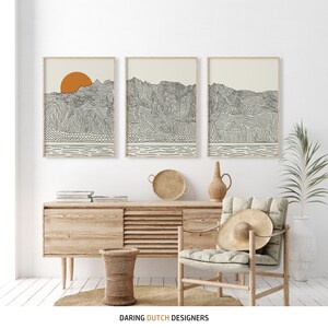 Triptych of Kauai Hawaii. The prints are beige with black lines, a bright orange sun and contain a view of the ocean, beach and mountains.