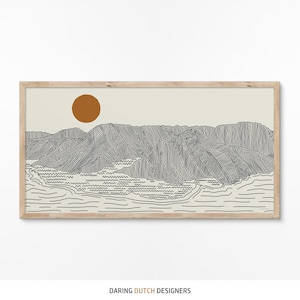 May include: A framed landscape art print featuring a mountain range and a sun in a minimalist style. The artwork is primarily black and white with a tan background and a brown sun. The frame is made of light-colored wood. The text "DARING DUTCH DESIGNERS" is at the bottom.