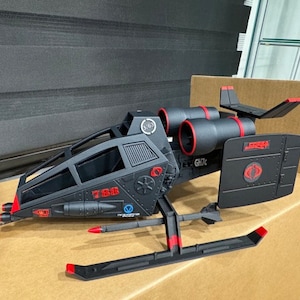 May include: Black and red toy helicopter with a Cobra logo and the text "786" on the side. The helicopter has a cockpit, two engines, and a tail.