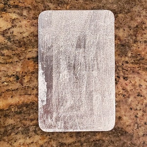 May include: A silver metal rectangle with a brushed finish.