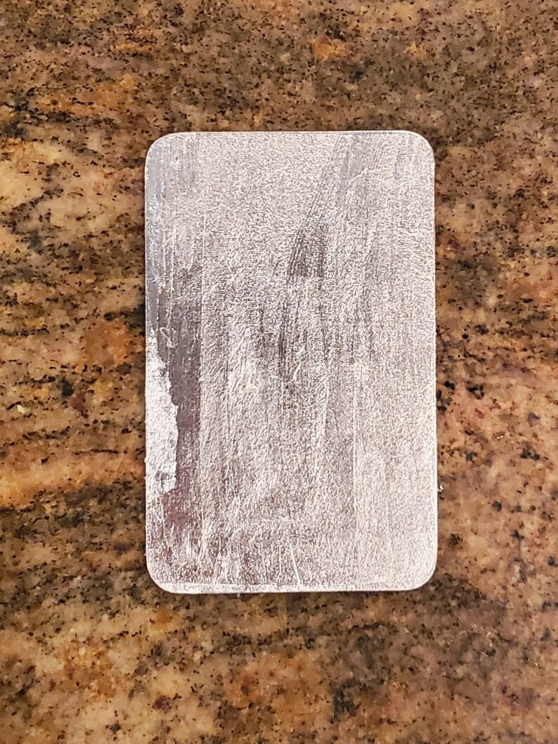 May include: A silver metal rectangle with a brushed finish.