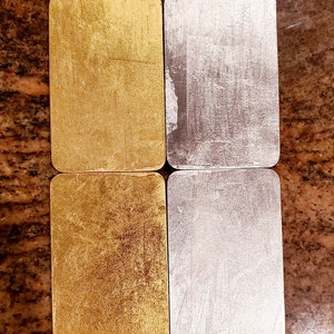 May include: Four rectangular tiles, two gold and two silver, with a brushed metallic finish. The tiles are arranged in two rows of two, with the gold tiles on top and the silver tiles on the bottom.