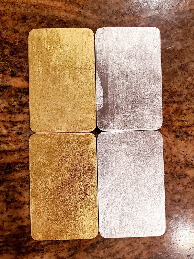 May include: Four rectangular tiles, two gold and two silver, with a brushed metallic finish. The tiles are arranged in two rows of two, with the gold tiles on top and the silver tiles on the bottom.