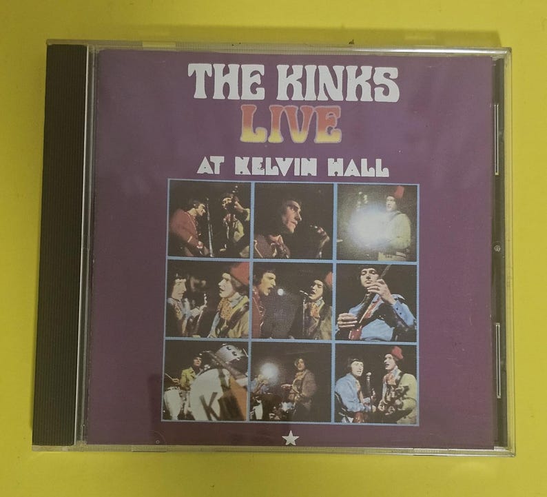 Op de afbeelding: Een paarse CD-hoes met een foto van de band The Kinks op de voorkant. De hoes heeft de titel "The Kinks Live at Kelvin Hall" erop gedrukt.