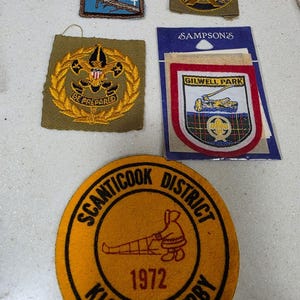 May include: A collection of five embroidered patches including a blue Fall-72 Campout patch, a circular Boy Scouts of America patch, a square Be Prepared patch, a Gilwell Park patch on a card, and a round orange Scanticook District Klondike Derby 1972 patch.