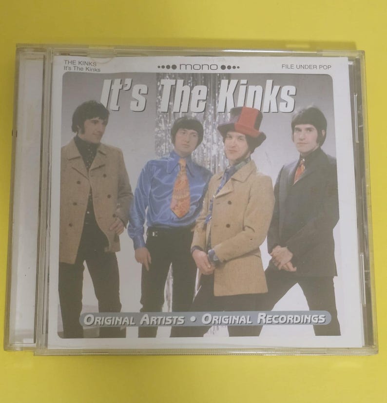 Op de afbeelding: Een CD-hoes met een foto van de band "The Kinks" op de voorkant. De bandleden dragen pakken en staan voor een zilveren achtergrond. De tekst "It's The Kinks" staat in grote letters op de voorkant van de hoes.