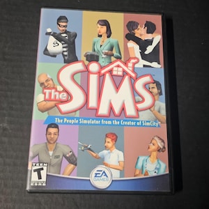 May include: The Sims PC game case. The cover features a colorful design with various character illustrations and the game's logo. The text reads "The Sims" and "The People Simulator from the Creator of SimCity". The game is rated "Teen" by ESRB.