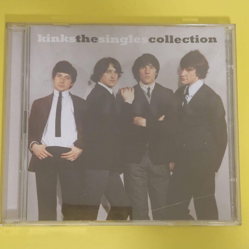 Op de afbeelding: Een CD-hoes met een foto van vier mannen in pak. De tekst op de hoes luidt "Kinks The Singles Collection".