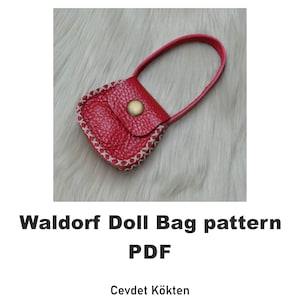 May include: A red leather doll bag with a white stitched trim and a gold button closure. The bag has a small handle and is on a white fuzzy surface. Waldorf Doll Bag pattern PDF.