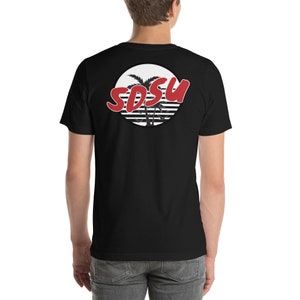 Peut inclure: T-shirt noir avec un graphique circulaire blanc représentant des palmiers et le texte "SDSU" en rouge.