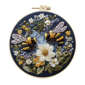 May include: Embroidered hoop art featuring two bumblebees surrounded by colorful flowers. The bees have black and yellow stripes, with detailed wings. The flowers include white daisies, yellow blooms, and purple accents, all set against a dark blue background.